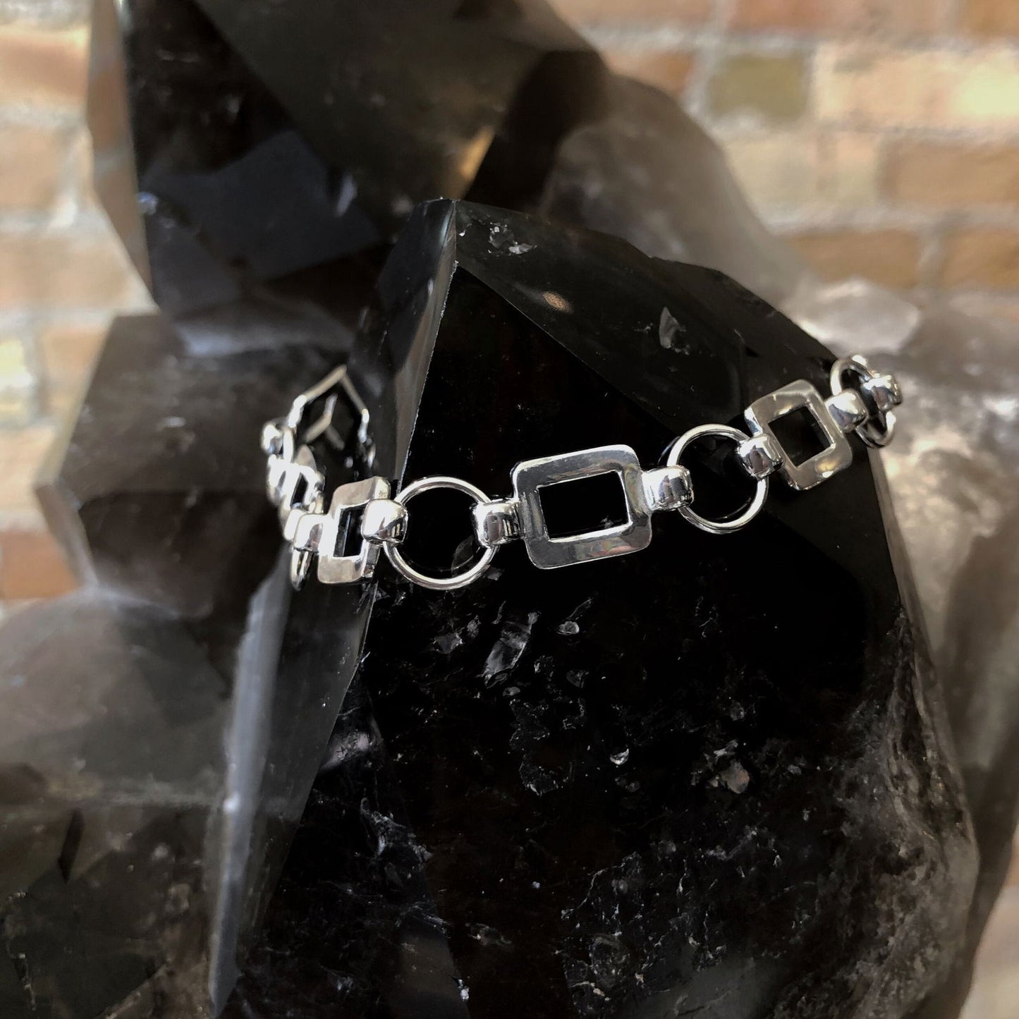 Photo of Square and Circle Fancy Link Bracelet in a decorative scene, designed by , available at Plumb Gold & Plumb Silver