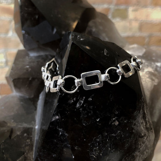 Photo of Square and Circle Fancy Link Bracelet in a decorative scene, designed by , available at Plumb Gold & Plumb Silver