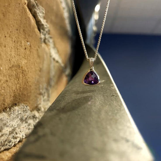 Photo of Stanton Color Trillion Amethyst Pendant in a decorative scene, designed by , available at Plumb Gold & Plumb Silver