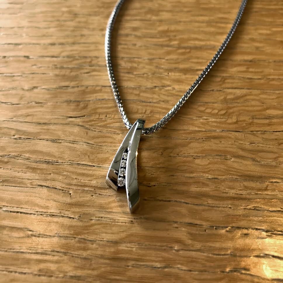 Photo of Swoop Diamond Slide Pendant in a decorative scene, designed by , available at Plumb Gold & Plumb Silver