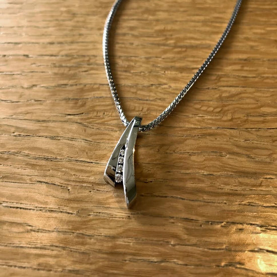 Photo of Swoop Diamond Slide Pendant in a decorative scene, designed by , available at Plumb Gold & Plumb Silver