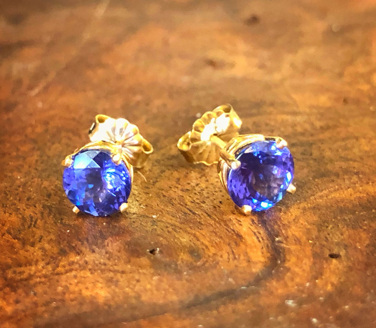 Photo of Tanzanite Stud Earrings in Yellow Gold in a decorative scene, designed by , available at Plumb Gold & Plumb Silver