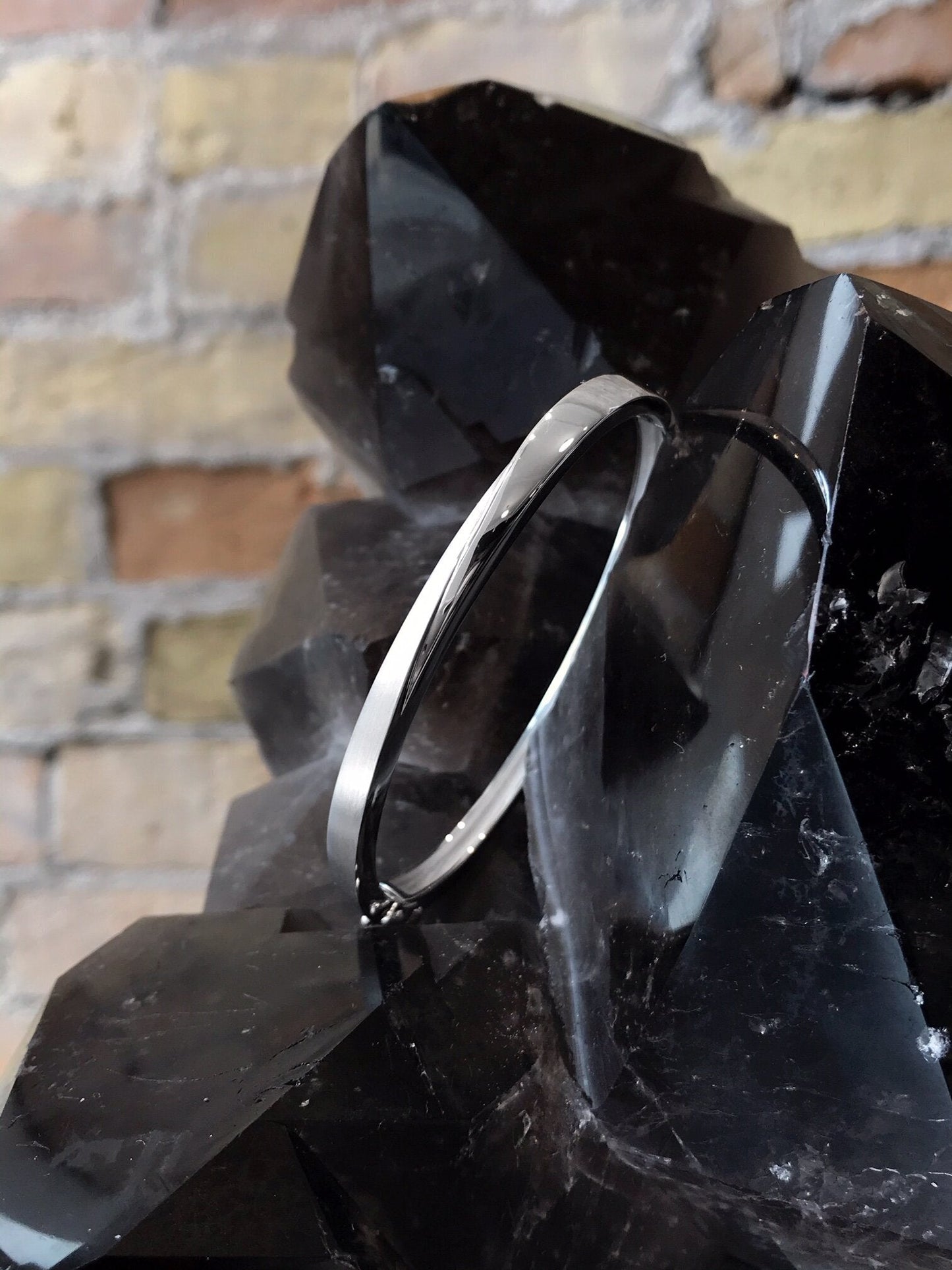 Photo of The Minimalist Bangle in a decorative scene, designed by , available at Plumb Gold & Plumb Silver
