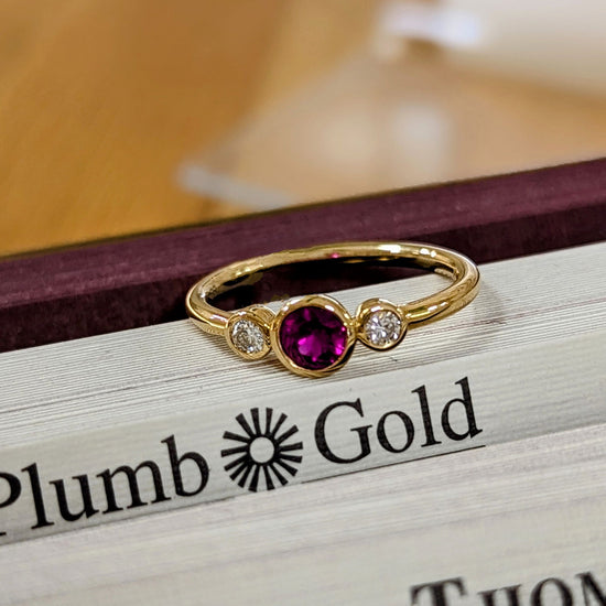 Photo of Three Stone Bezel Ring in a decorative scene, designed by , available at Plumb Gold & Plumb Silver