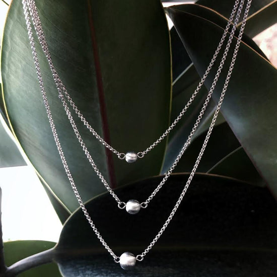 Photo of Three Strand Stardust Bead Necklace in a decorative scene, designed by , available at Plumb Gold & Plumb Silver