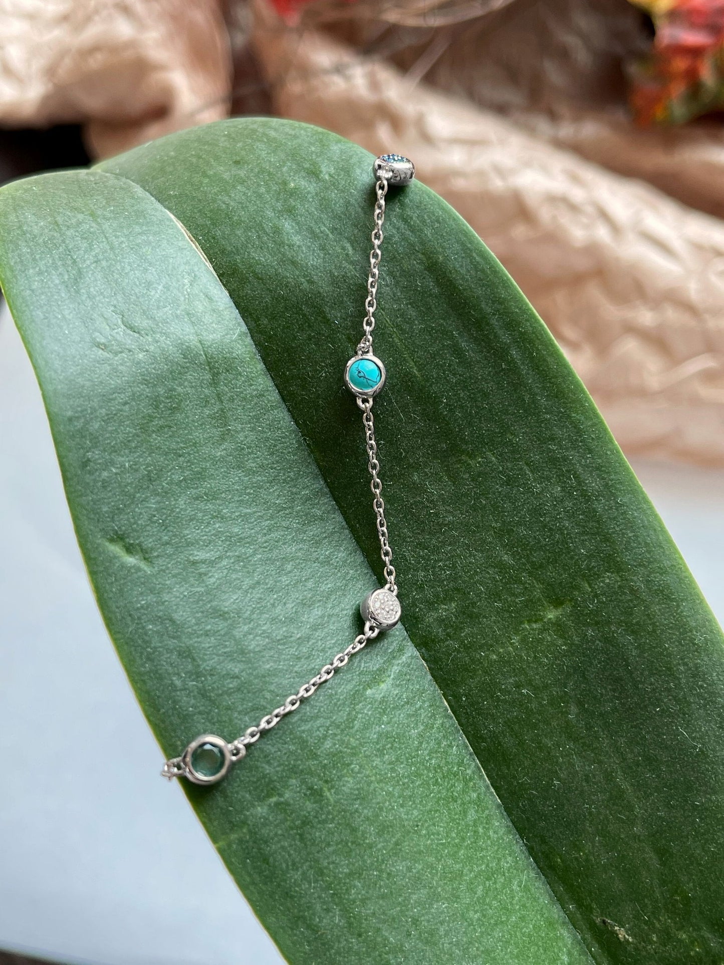 Photo of Turquoise and Cubic Zirconia Station Bracelet in a decorative scene, designed by , available at Plumb Gold & Plumb Silver