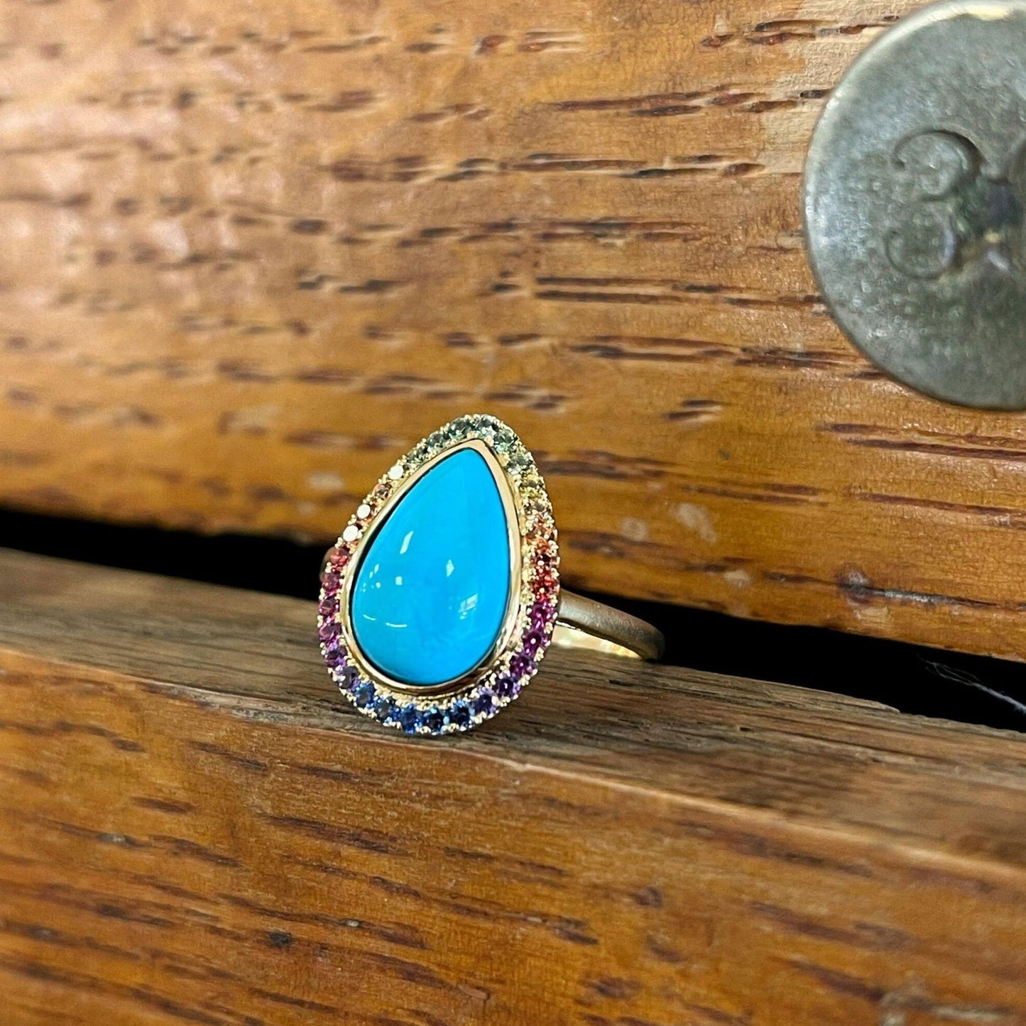 Photo of Turquoise and Rainbow Sapphire Ring in a decorative scene, designed by , available at Plumb Gold & Plumb Silver