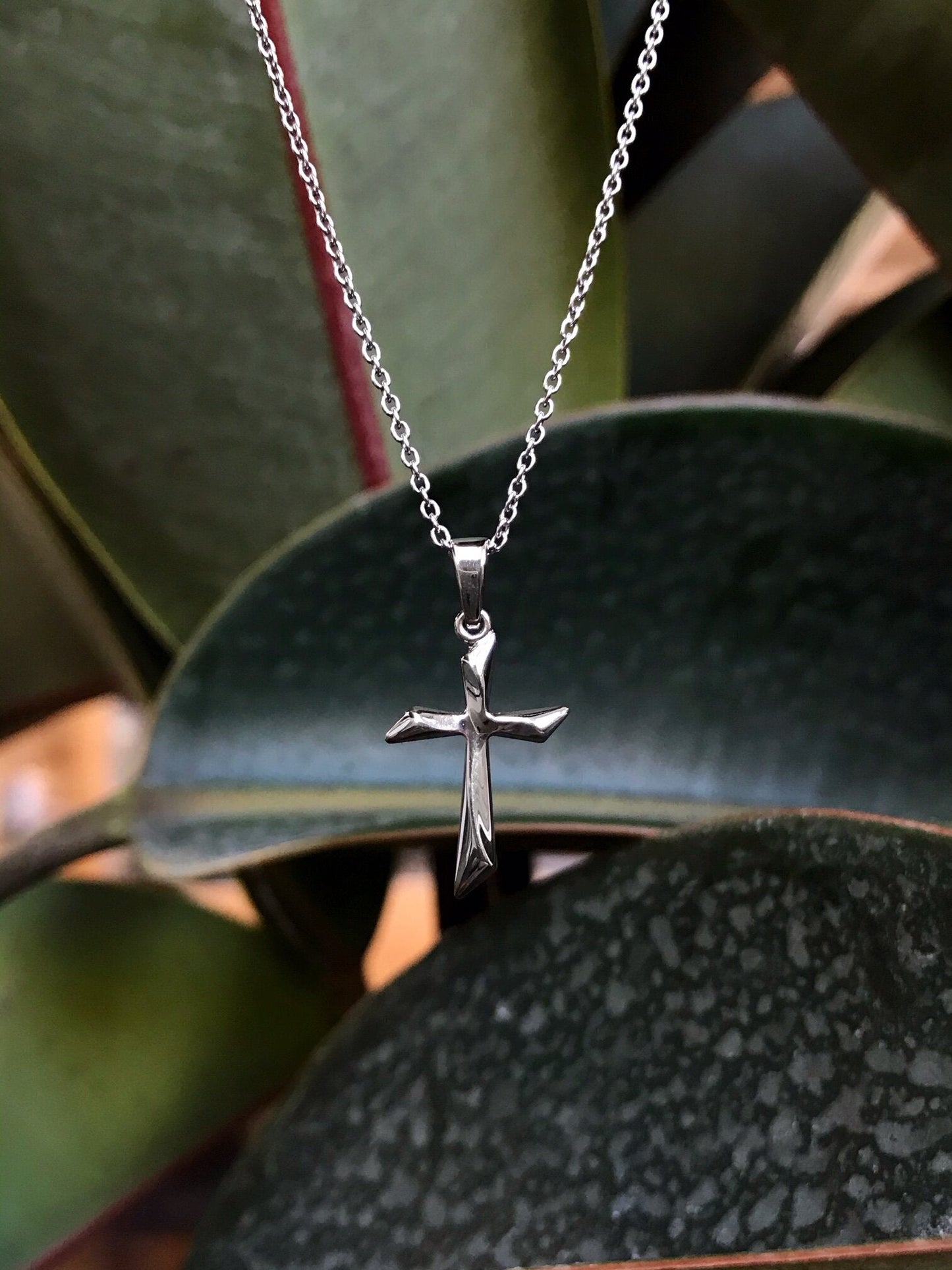 Photo of Twisted Cross Necklace in a decorative scene, designed by , available at Plumb Gold & Plumb Silver