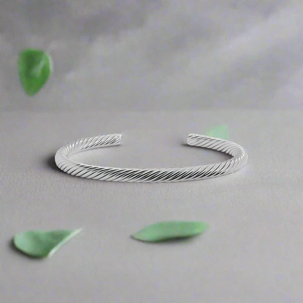 Photo of Twisted Cuff Bracelet in a decorative scene, designed by , available at Plumb Gold & Plumb Silver