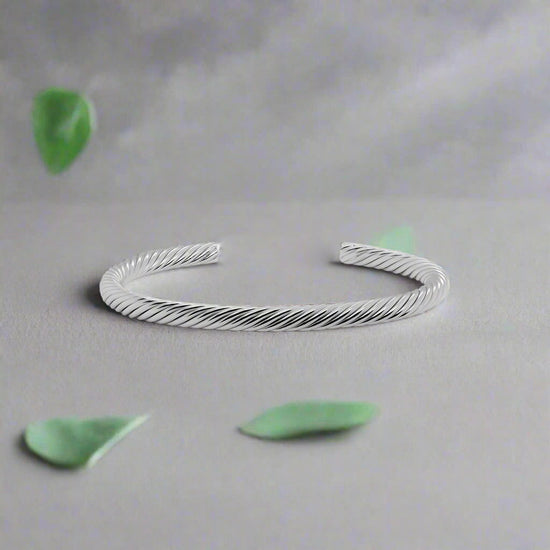 Photo of Twisted Cuff Bracelet in a decorative scene, designed by , available at Plumb Gold & Plumb Silver