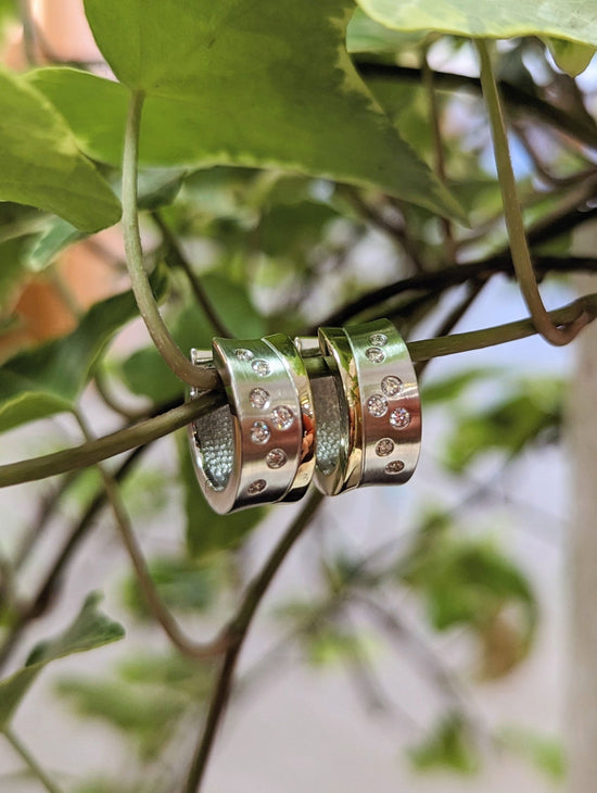 Photo of Two-tone Modern Accented Huggie Earrings in a decorative scene, designed by , available at Plumb Gold & Plumb Silver