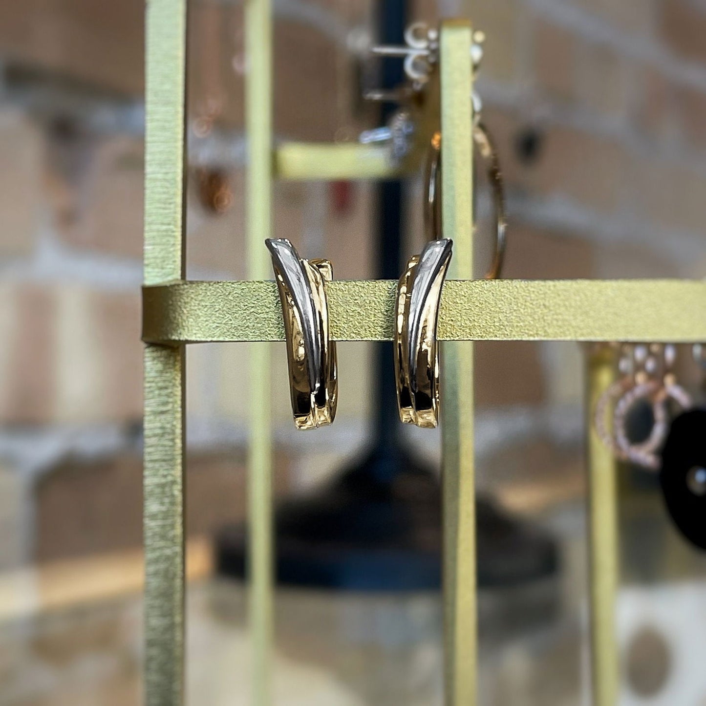 Photo of Two-tone Swoop Huggies in a decorative scene, designed by , available at Plumb Gold & Plumb Silver