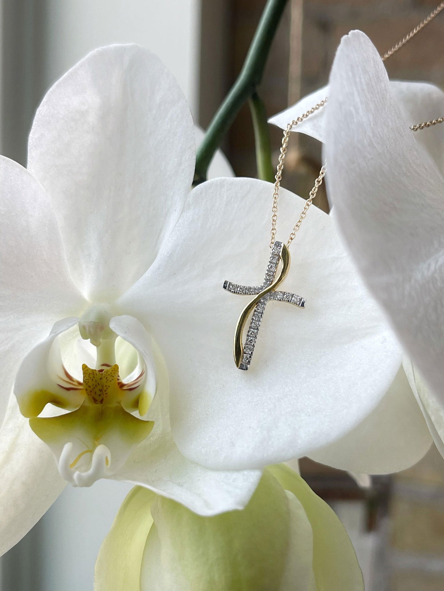 Photo of Wave Two-Tone Diamond Cross Necklace in a decorative scene, designed by , available at Plumb Gold & Plumb Silver