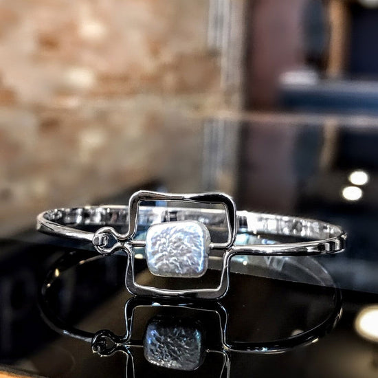 Photo of "Zenith" Bangle in a decorative scene, designed by , available at Plumb Gold & Plumb Silver