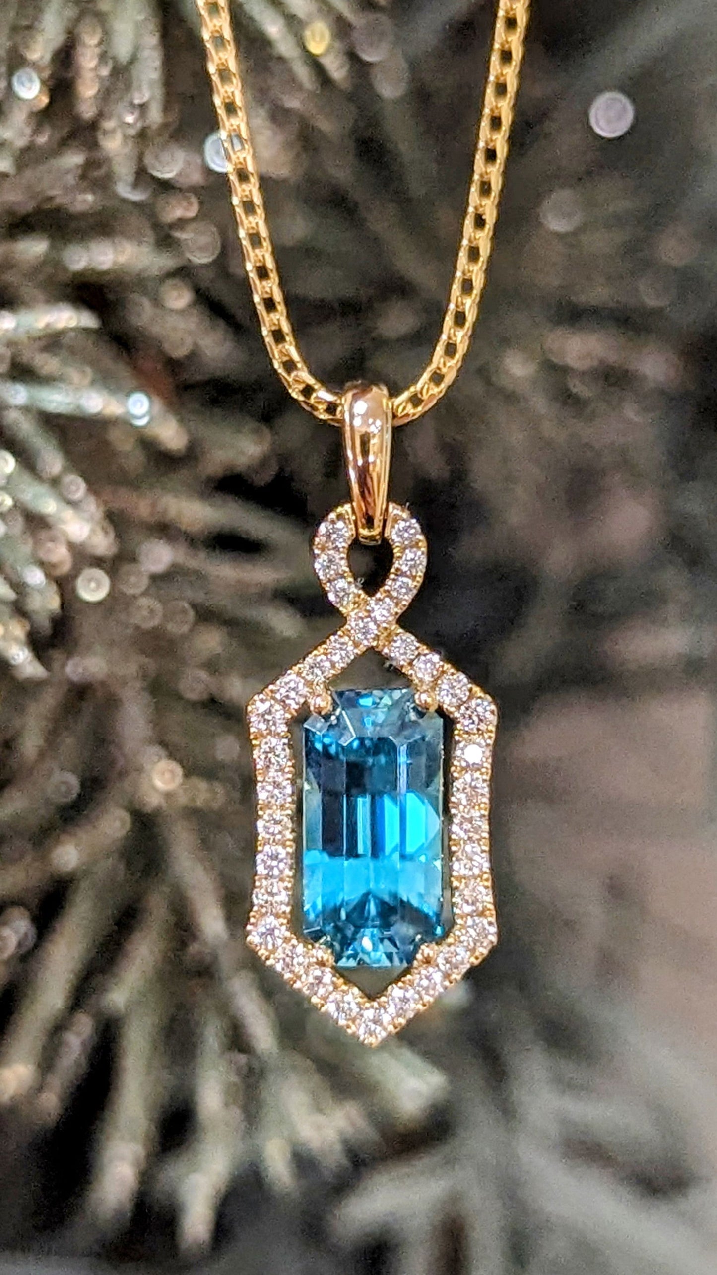 Photo of Zoma Blue Zircon Halo Pendant in a decorative scene, designed by , available at Plumb Gold & Plumb Silver