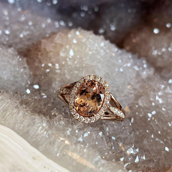 Photo of Zoma Color Malaya Garnet &amp; Diamond Halo Ring in a decorative scene, designed by , available at Plumb Gold & Plumb Silver