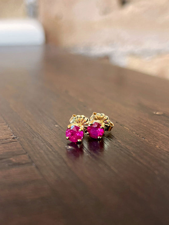 Photo of Zoma Color Ruby Studs in a decorative scene, designed by , available at Plumb Gold & Plumb Silver